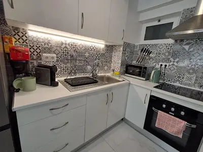 a small kitchen with white cabinets and a sink at Cozy Airport Apartment in Machico
