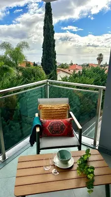 a table on a balcony with a chair and a plate on it at Ocean View Oasis Funchal with Parking in Funchal