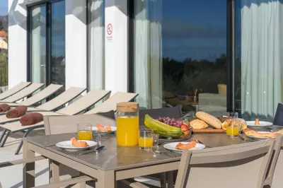 a table with a plate of fruit and juice on it at OurMadeira - Casa Laranja in Prazeres