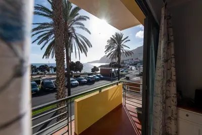 a balcony with a view of a parking lot and palm trees at Apartamentos Amarelo in Caniçal