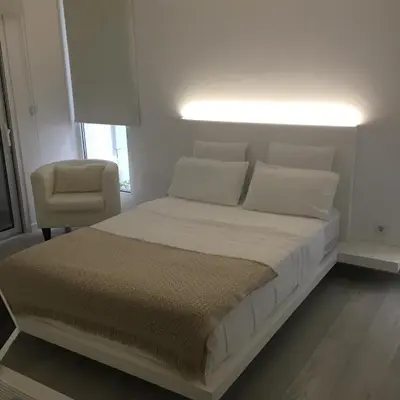 a white bedroom with a bed and a chair at White Studio in Câmara de Lobos