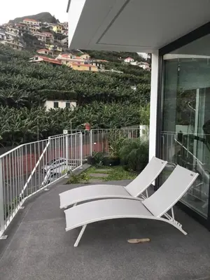 a white chair sitting on the balcony of a house at White Studio in Câmara de Lobos