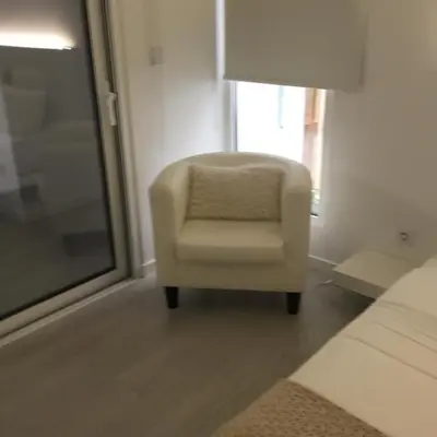 a white chair sitting in a room with a window at White Studio in Câmara de Lobos