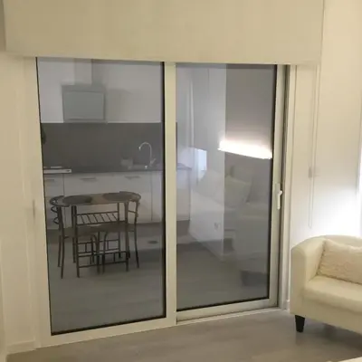a sliding glass door in a living room with a table at White Studio in Câmara de Lobos