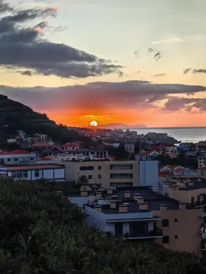 a sunset over a city with buildings and the ocean at White Studio in Câmara de Lobos