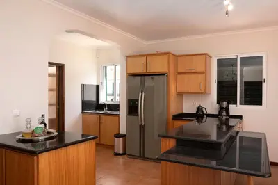 a kitchen with wooden cabinets and a stainless steel refrigerator at Solful at the Nomads Village Ponta do Sol in Ponta do Sol