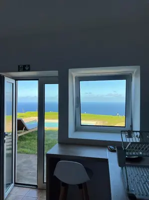 a room with two windows and a desk with a chair at Casa das Vacas - Retreat House in Ponta do Pargo