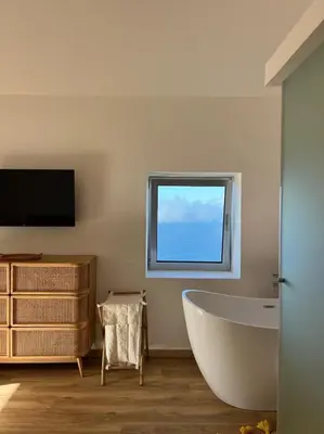 a bathroom with a tub and a tv and a window at Casa das Vacas - Retreat House in Ponta do Pargo