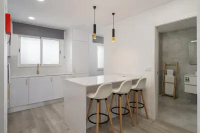a kitchen with white cabinets and a counter with stools at Central Park Caniço Central Modern & Cozy in Santa Cruz