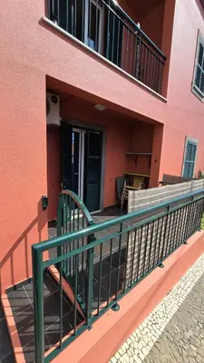 a balcony of a pink building with a green railing at Jardim do Sol in Nogueira