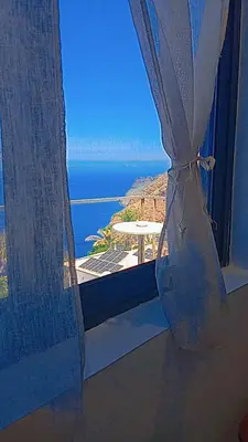 an open window with a view of the ocean at Farol views in Fajã da Ovelha
