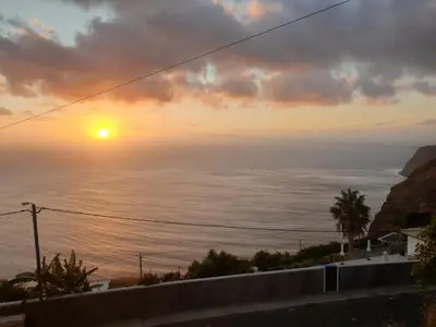 a sunset from the balcony of a house at Farol views in Fajã da Ovelha