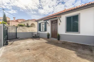 a white house with a patio and a gate at Casa da Badé in Funchal