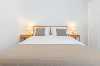 a bedroom with a large white bed with two lamps at Casa da Badé in Funchal