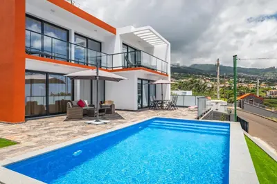 an orange and white house with a green yard at Sea view flat in Casa Teixeira Calheta Madeira in Estreito da Calheta
