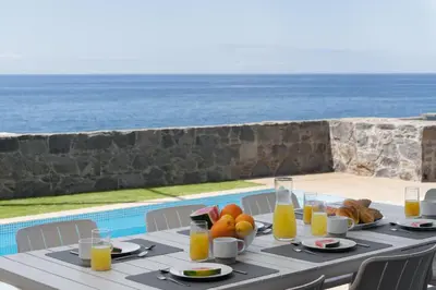 a table with food and orange juice on it with the ocean at OurMadeira - BeachFront in Madalena do Mar