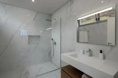 a white bathroom with a shower and a sink at OurMadeira - BeachFront in Madalena do Mar