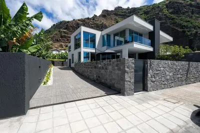 a large white house with a stone wall at OurMadeira - BeachFront in Madalena do Mar