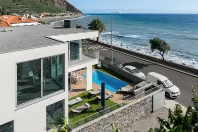 a house with a swimming pool next to the ocean at OurMadeira - BeachFront in Madalena do Mar