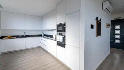 a white kitchen with white cabinets and black appliances at Garachico Vista by LovelyStay in Estreito de Câmara de Lobos
