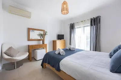 a bedroom with a bed and a chair and a window at Briso do Mós in Lagos