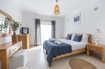 a bedroom with a bed and a desk and a tv at Briso do Mós in Lagos