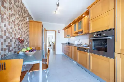 a kitchen with wooden cabinets and a bowl of fruit on a table at Briso do Mós in Lagos
