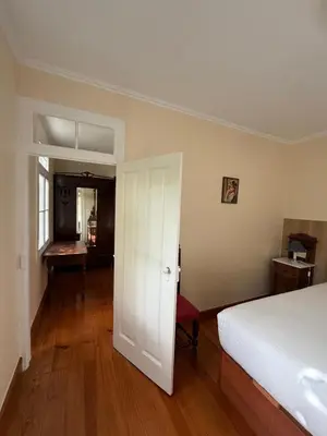 a bedroom with a white bed and a wooden floor at Casa da Cruz in Ponta do Sol