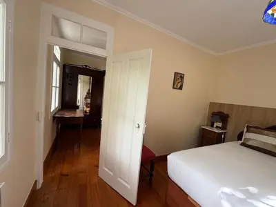 a bedroom with a white bed and a room with a desk at Casa da Cruz in Ponta do Sol