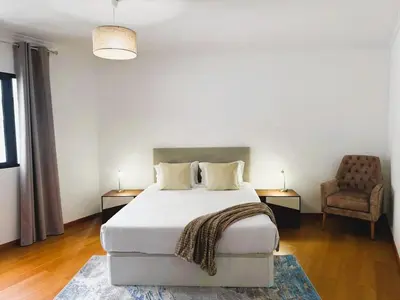 a bedroom with a large bed and a chair at C Center Apartment in Funchal