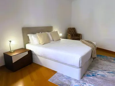 a bedroom with a large white bed and a chair at C Center Apartment in Funchal