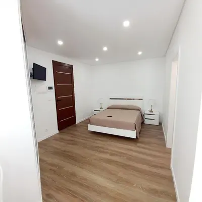 a white bedroom with a bed and a wooden floor at Casa Rodrigues in Madalena do Mar
