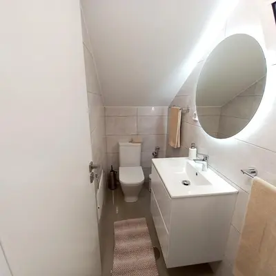 a white bathroom with a sink and a mirror at Casa Rodrigues in Madalena do Mar