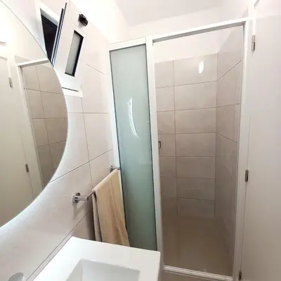 a bathroom with a shower with a sink and a mirror at Casa Rodrigues in Madalena do Mar