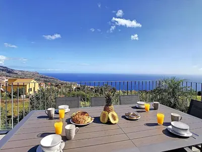 a wooden table with food and a view of the ocean at New Villa Piece of Heaven by Your Madeira Rentals in Estreito da Calheta
