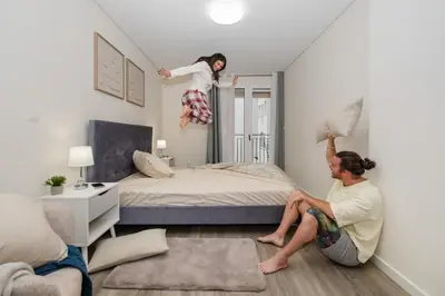 a woman sitting on the floor while a girl is jumping on a bed at Carmo - Moon in Funchal