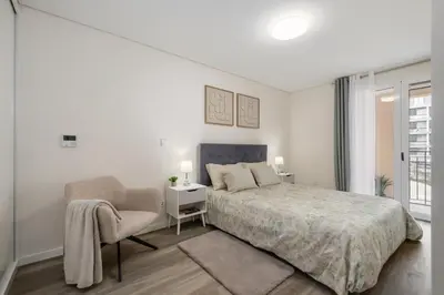 a white bedroom with a bed and a chair at Carmo - Moon in Funchal