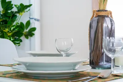 a table with plates and glasses and a vase at GREEN OASIS FUNCHAL HOUSE WITH 2 PRIVATE APARTMENTS and TERRACE in Funchal