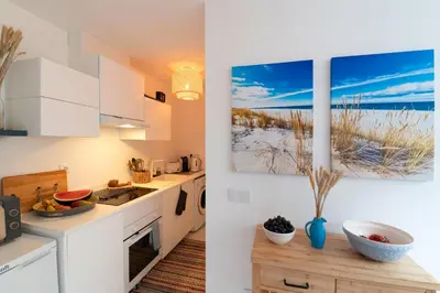 a kitchen with white cabinets and a painting on the wall at GREEN OASIS FUNCHAL HOUSE WITH 2 PRIVATE APARTMENTS and TERRACE in Funchal