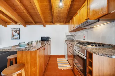 a kitchen with wooden cabinets and a counter with stools at Casa Katy by Atlântica in Calheta