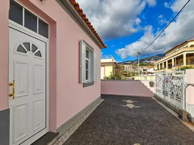 a pink house with a white door and a balcony at Sunny House Funchal in Funchal