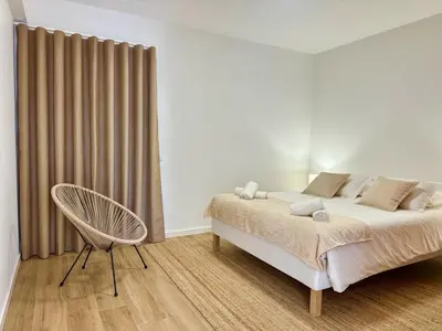 a white bedroom with a bed and a chair at Villa Arrifes Porto Santo in Porto Santo