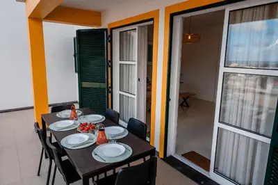 a dining room with a table and chairs and a balcony at Villa Arrifes Porto Santo in Porto Santo