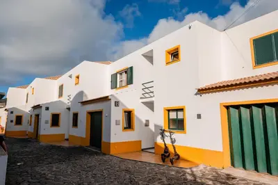 a row of white buildings with green doors at Villa Arrifes Porto Santo in Porto Santo