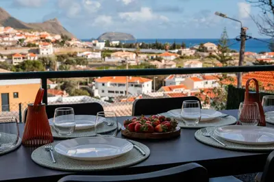 a table with plates and glasses and a bowl of fruit at Villa Arrifes Porto Santo in Porto Santo
