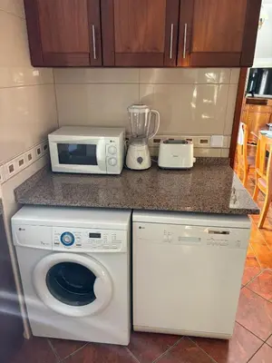 a kitchen with a washing machine and a microwave at Sea & Mountain View Home in Machico in Machico