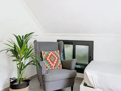 a chair and a plant in a room with a bed at Villa Paixao by Atlantic Holiday in Machico