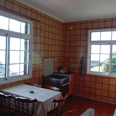 a kitchen with a table and two windows at Yellow Owl II Bedroom I in Campanário