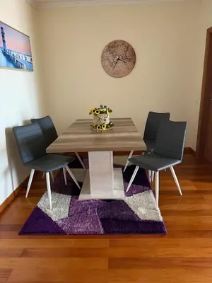 a dining room table with two chairs and a clock on the wall at A&CSuite in Caniço