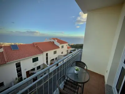 a balcony with a table and chairs and the ocean at A&CSuite in Caniço